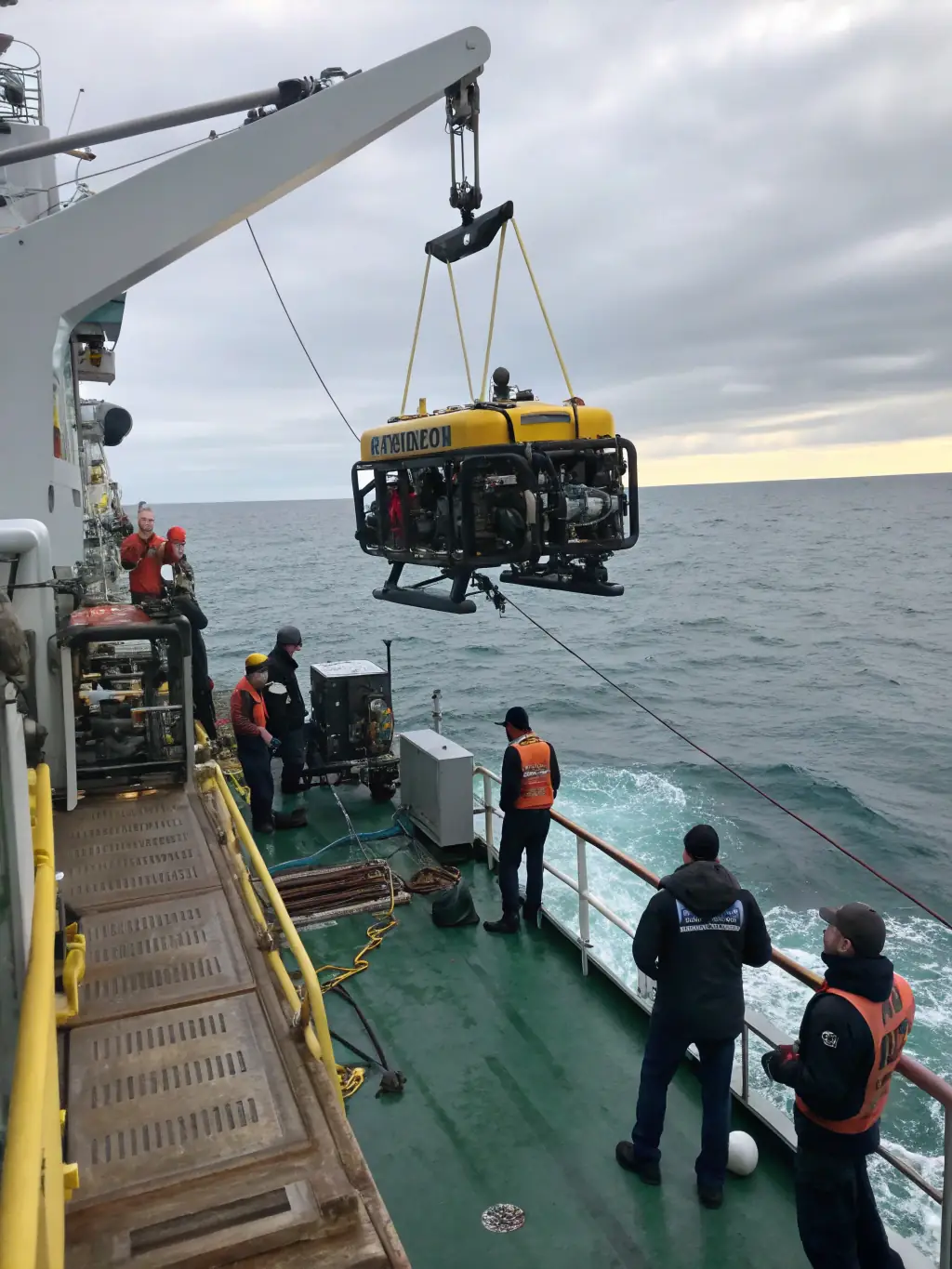 An image showcasing a remotely operated vehicle (ROV) being launched from a support vessel, ready to descend into the ocean for a recovery mission.